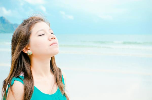 woman eyes closed smelling, sea in background